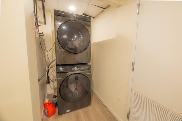 laundry room featuring light wood-type flooring and stacked washer and clothes dryer