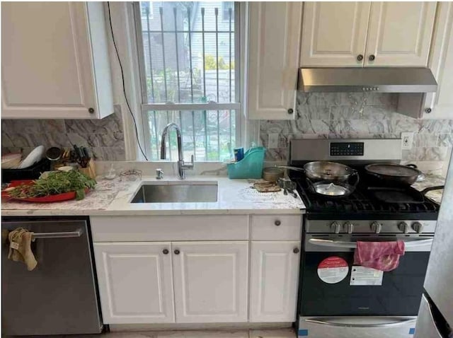 kitchen with backsplash, white cabinets, sink, and stainless steel appliances