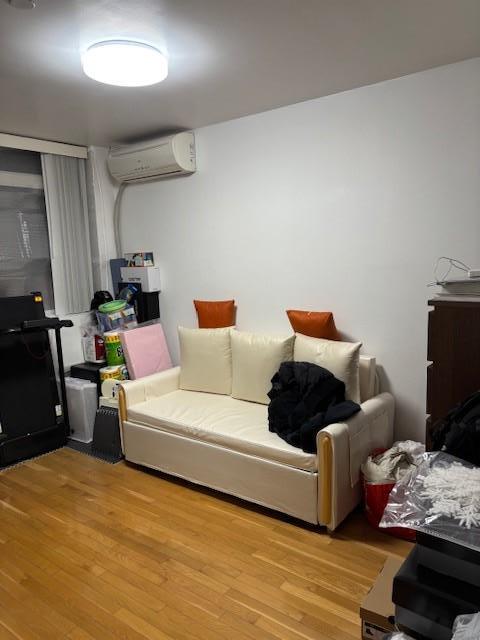 living room with light wood-type flooring and a wall unit AC