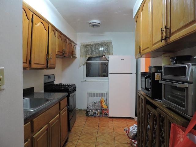 kitchen featuring radiator, sink, light tile patterned flooring, and black appliances