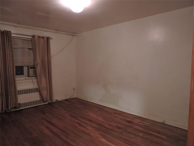 spare room featuring dark wood-type flooring and radiator