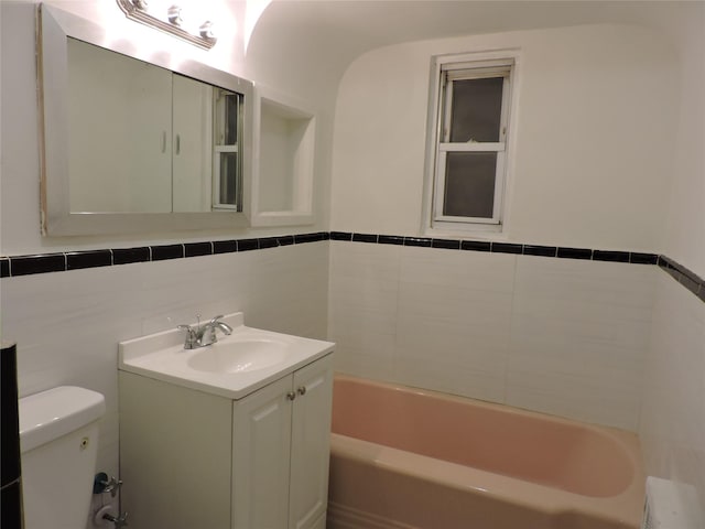 bathroom featuring a bathtub, vanity, tile walls, and toilet