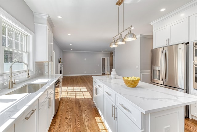 kitchen with white cabinets, a center island, appliances with stainless steel finishes, and light hardwood / wood-style flooring