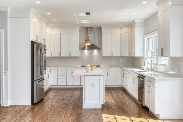 kitchen with wall chimney exhaust hood, stainless steel appliances, a kitchen island, pendant lighting, and white cabinets