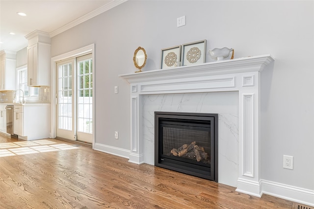 details featuring a high end fireplace, wood-type flooring, stainless steel dishwasher, and ornamental molding