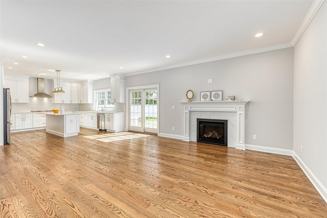 unfurnished living room featuring a fireplace, sink, light hardwood / wood-style flooring, and ornamental molding