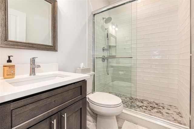 bathroom with tile patterned floors, vanity, toilet, and a shower with door