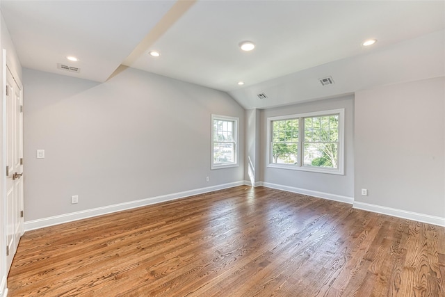 empty room with light hardwood / wood-style flooring and lofted ceiling