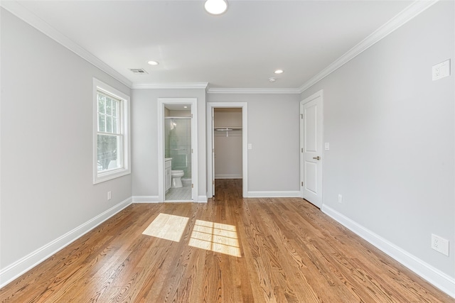 unfurnished bedroom with connected bathroom, light hardwood / wood-style flooring, a spacious closet, and crown molding