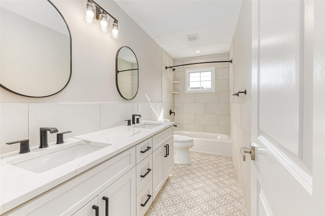 full bathroom with tiled shower / bath, vanity, toilet, and tile walls