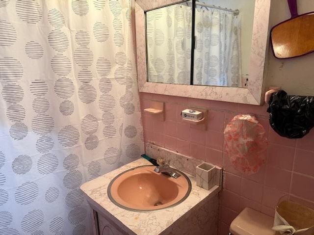 bathroom with vanity, toilet, and tile walls