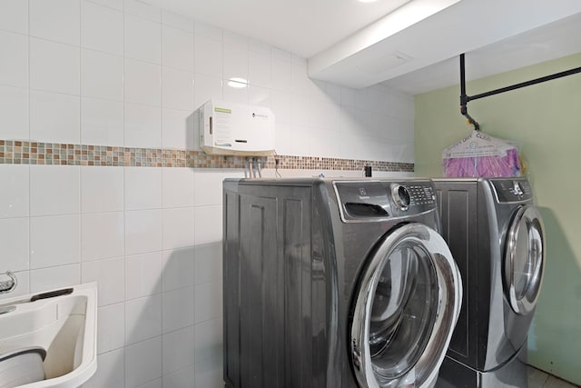 laundry room featuring independent washer and dryer and tile walls