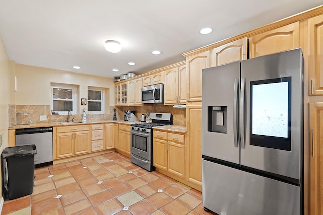 kitchen with decorative backsplash, stainless steel appliances, sink, light brown cabinets, and light tile patterned floors