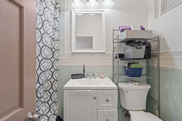 bathroom featuring vanity, tile walls, and toilet