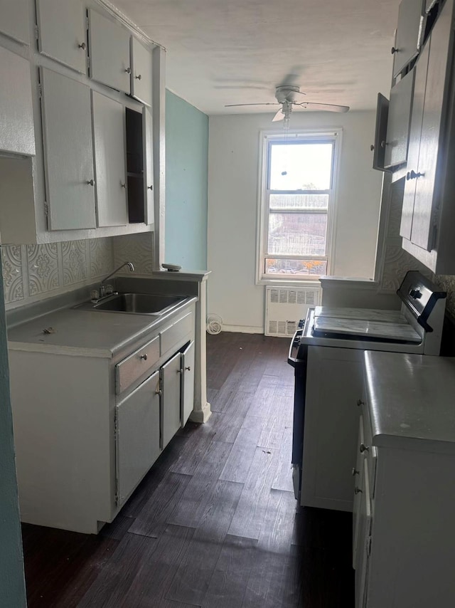 kitchen featuring stove, dark hardwood / wood-style floors, white cabinetry, and radiator