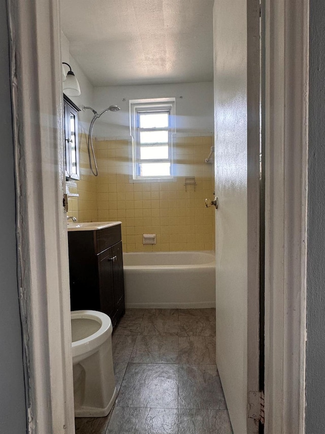 full bathroom with vanity, tiled shower / bath combo, toilet, a textured ceiling, and tile walls