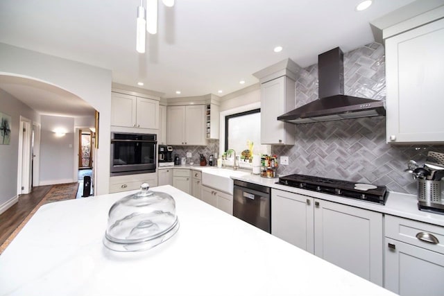 kitchen featuring dishwasher, sink, wall chimney exhaust hood, black oven, and dark hardwood / wood-style flooring