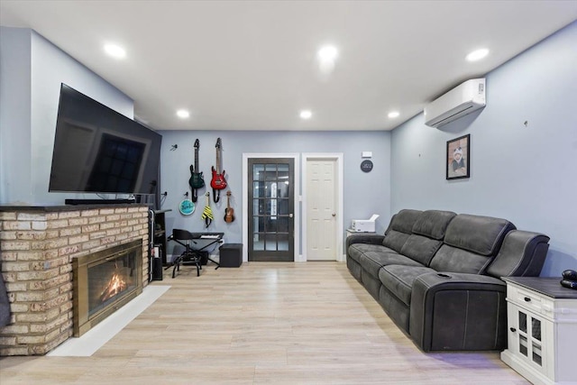 living room featuring a fireplace, a wall mounted AC, and light hardwood / wood-style flooring