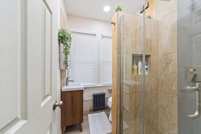 bathroom with vanity, toilet, walk in shower, and radiator