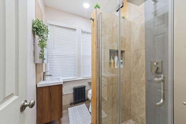 bathroom with vanity, toilet, radiator heating unit, and a shower with door