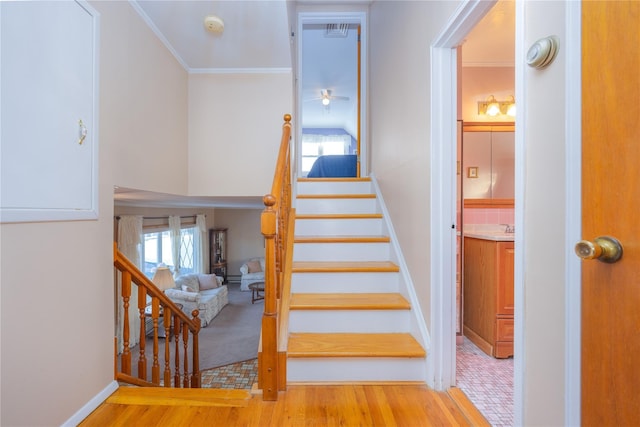 staircase with crown molding and hardwood / wood-style flooring