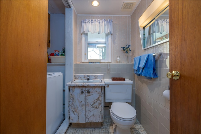 bathroom with tile walls, vanity, washer / clothes dryer, tile patterned floors, and toilet