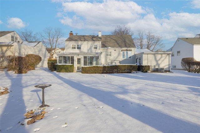 snow covered house featuring a sunroom