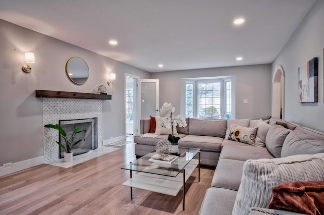 living room featuring a tiled fireplace and light hardwood / wood-style floors