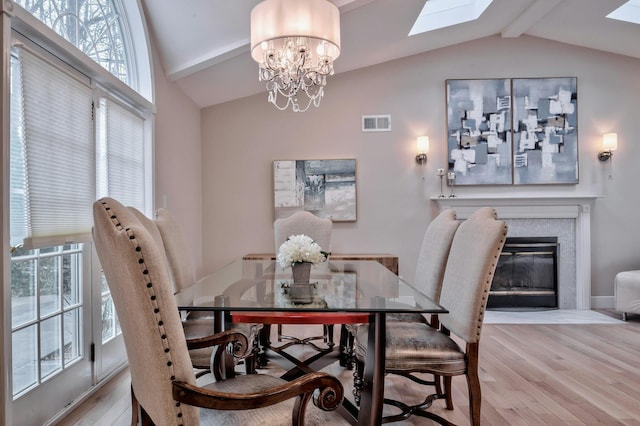 dining room with lofted ceiling with skylight, a chandelier, and hardwood / wood-style flooring