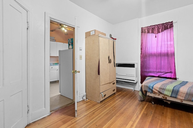 bedroom with white fridge, light wood-type flooring, and heating unit