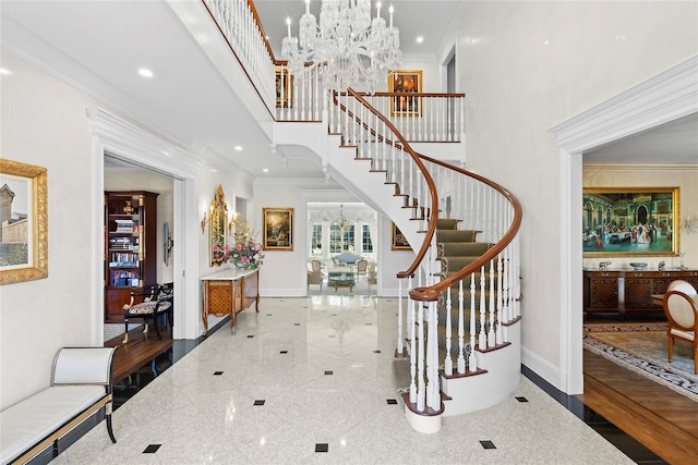 foyer entrance featuring a notable chandelier, a towering ceiling, and crown molding