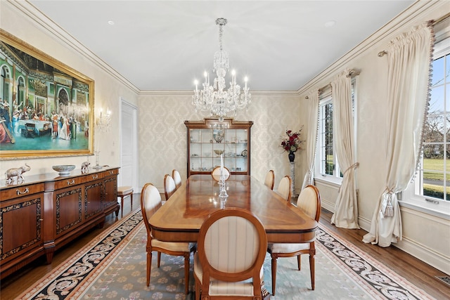 dining space with an inviting chandelier, ornamental molding, and hardwood / wood-style flooring