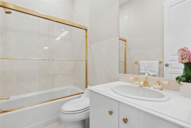 full bathroom featuring shower / bath combination with glass door, vanity, tile walls, and toilet