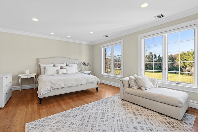 bedroom featuring light hardwood / wood-style floors, multiple windows, and ornamental molding