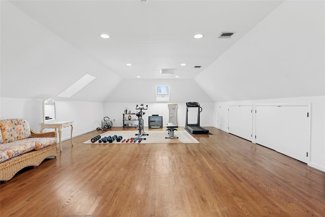 exercise room featuring wood-type flooring and lofted ceiling with skylight