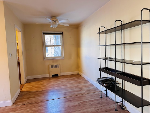 spare room with radiator, ceiling fan, and light wood-type flooring