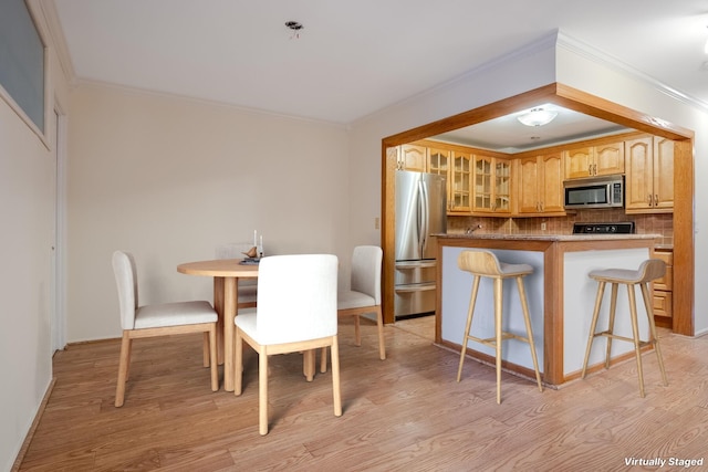 kitchen featuring tasteful backsplash, a breakfast bar area, light hardwood / wood-style flooring, and appliances with stainless steel finishes