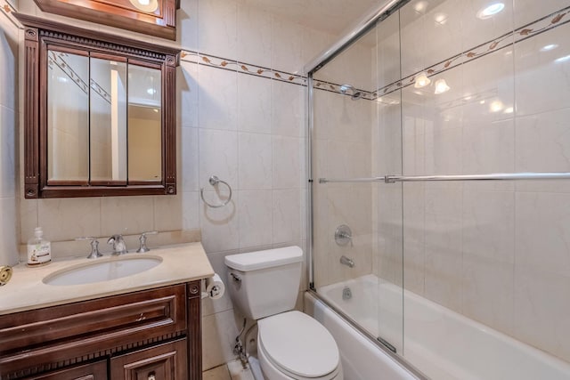 full bathroom with vanity, combined bath / shower with glass door, tile walls, and toilet