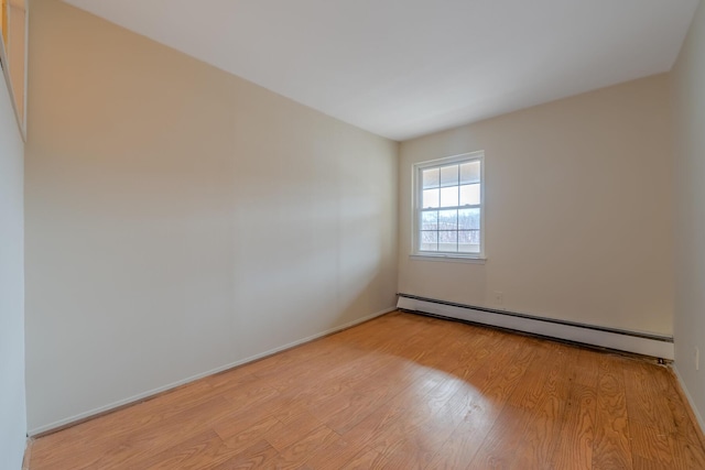 spare room with a baseboard heating unit and light hardwood / wood-style floors