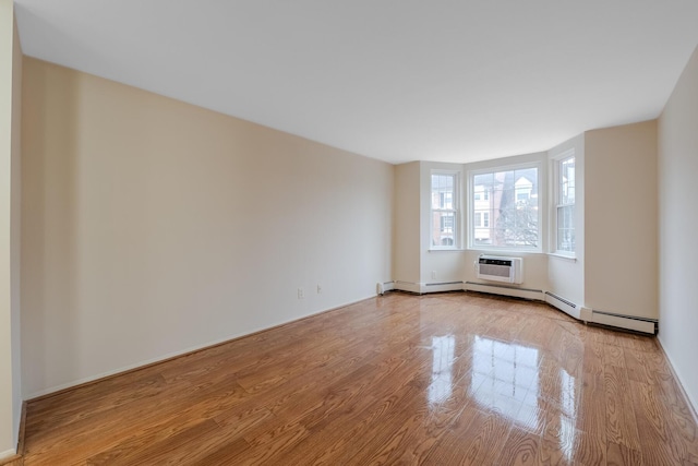 unfurnished room featuring an AC wall unit and light hardwood / wood-style floors