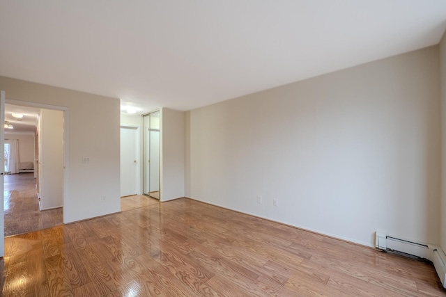 empty room featuring a baseboard radiator and light wood-type flooring