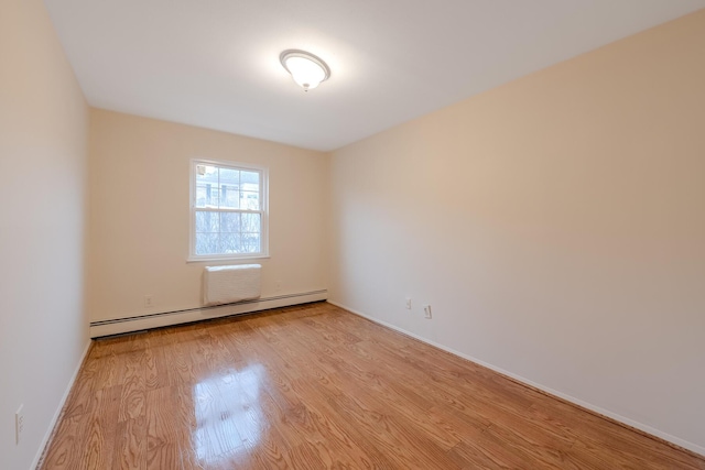 spare room featuring a baseboard heating unit and light hardwood / wood-style flooring