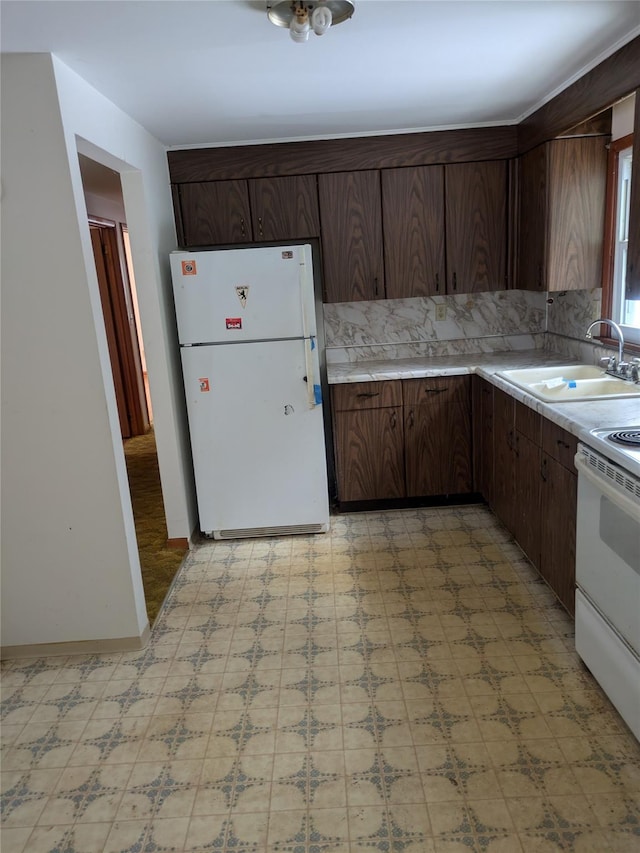 kitchen with white appliances, backsplash, dark brown cabinetry, and sink