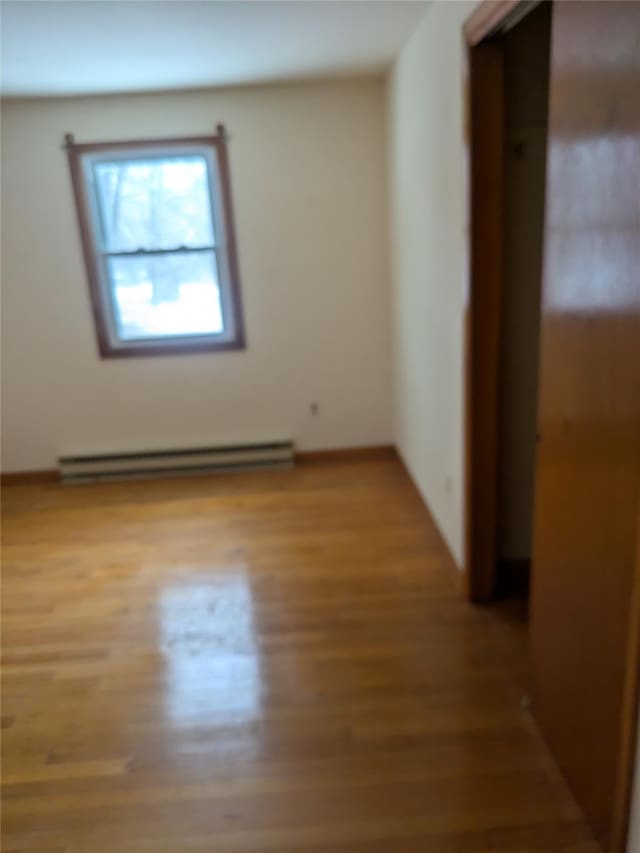 spare room with a baseboard radiator and light hardwood / wood-style floors