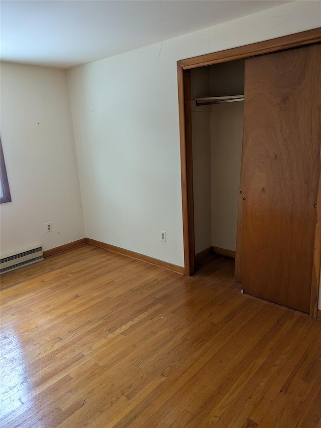 unfurnished bedroom with a closet, light hardwood / wood-style floors, and a baseboard radiator