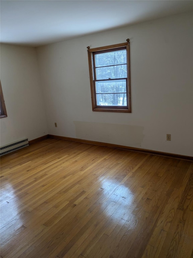 spare room featuring light wood-type flooring and a baseboard radiator