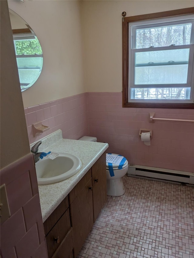 bathroom with a baseboard radiator, tile patterned flooring, toilet, vanity, and tile walls