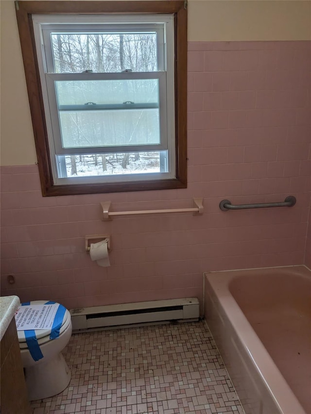 bathroom featuring a bath, a healthy amount of sunlight, and a baseboard heating unit