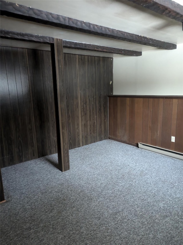 basement featuring carpet flooring, wooden walls, and baseboard heating