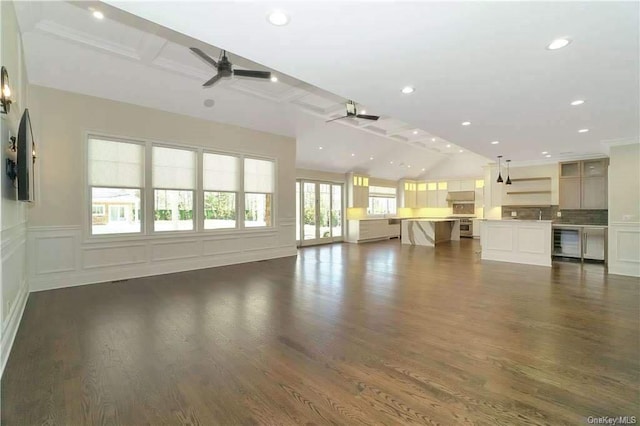 unfurnished living room featuring beverage cooler, a decorative wall, a ceiling fan, and dark wood-style flooring